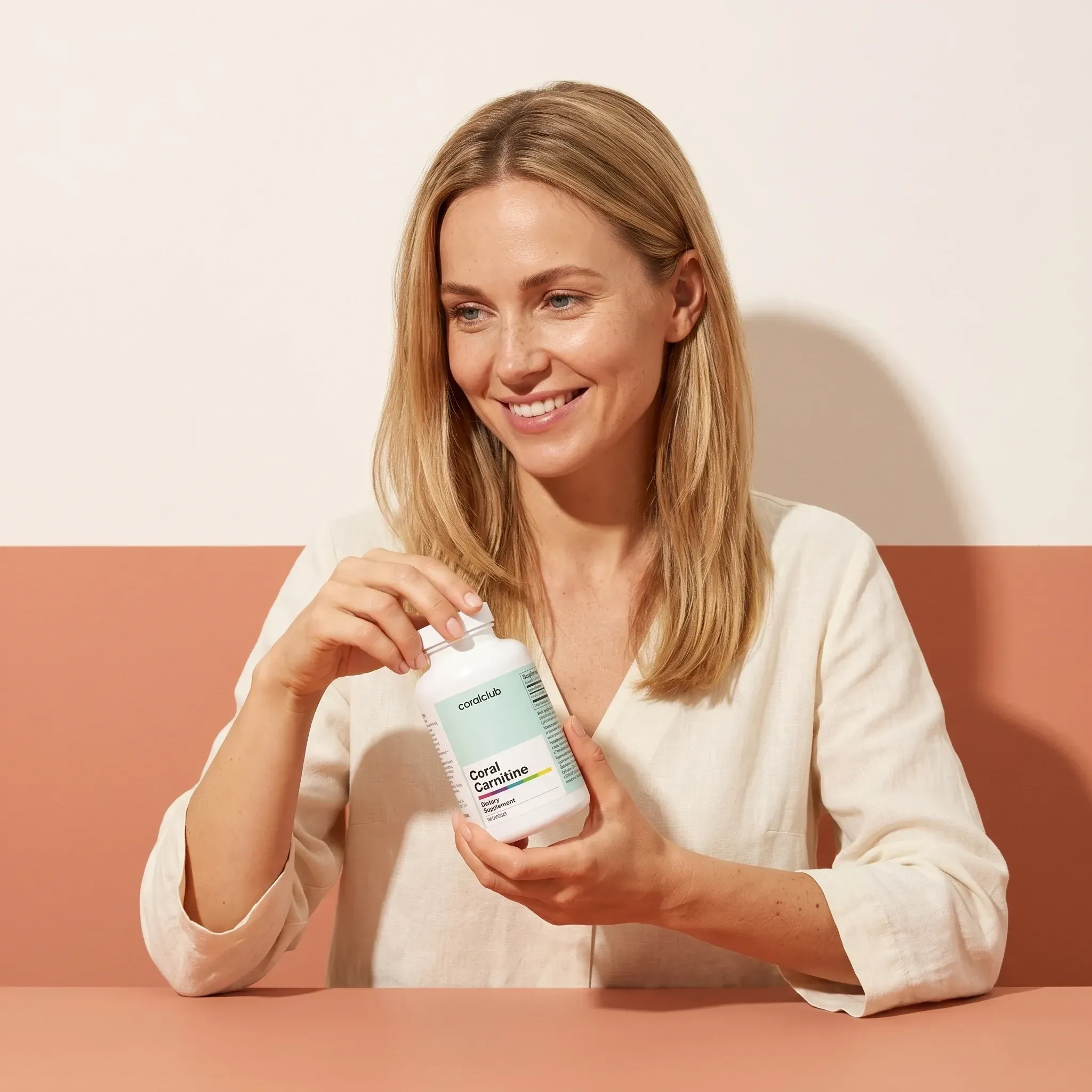 Woman holding Coral Carnitine supplement bottle in a minimalist lifestyle setting.