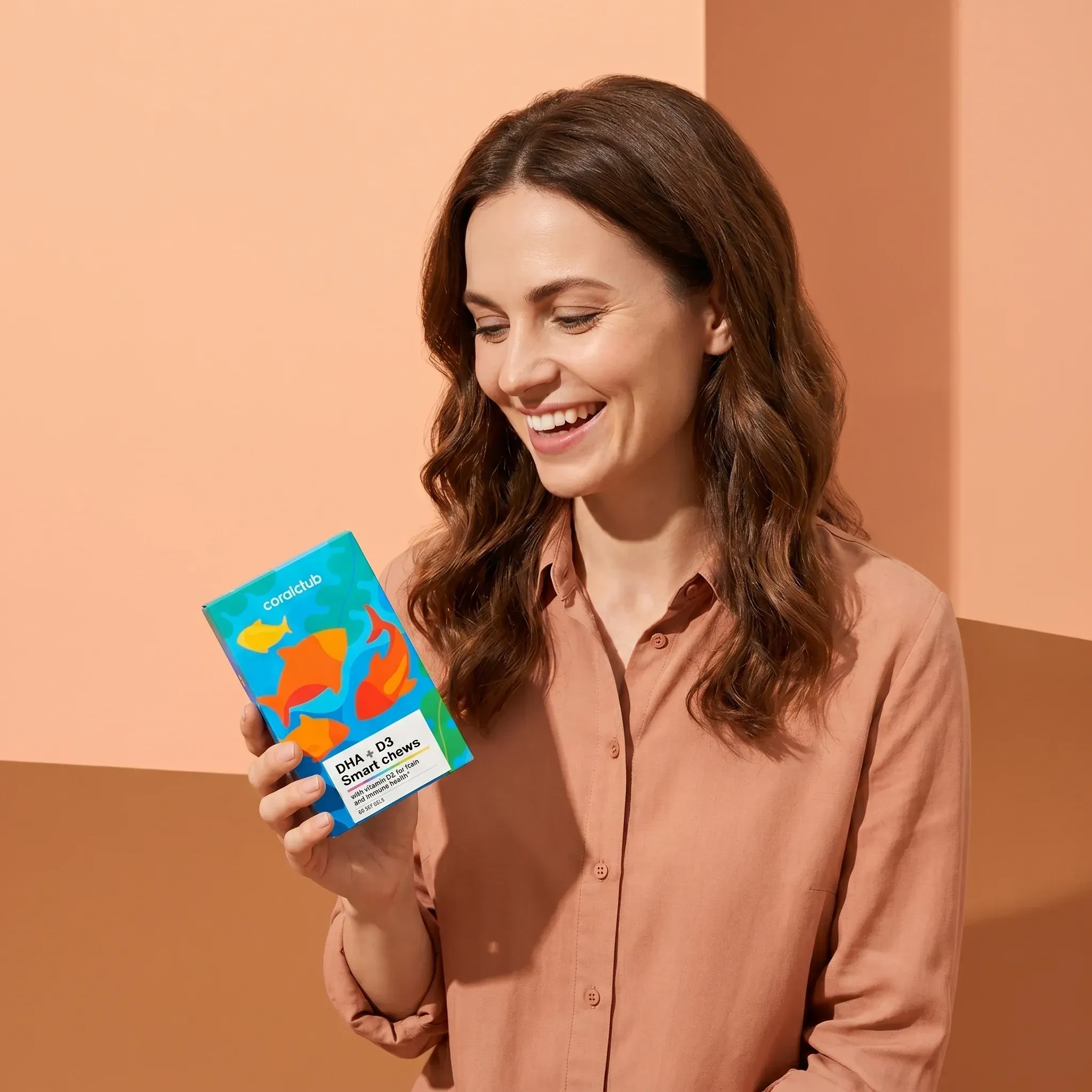 Woman smiling while holding DHA + D3 Smart Chews packaging against a colorful background.