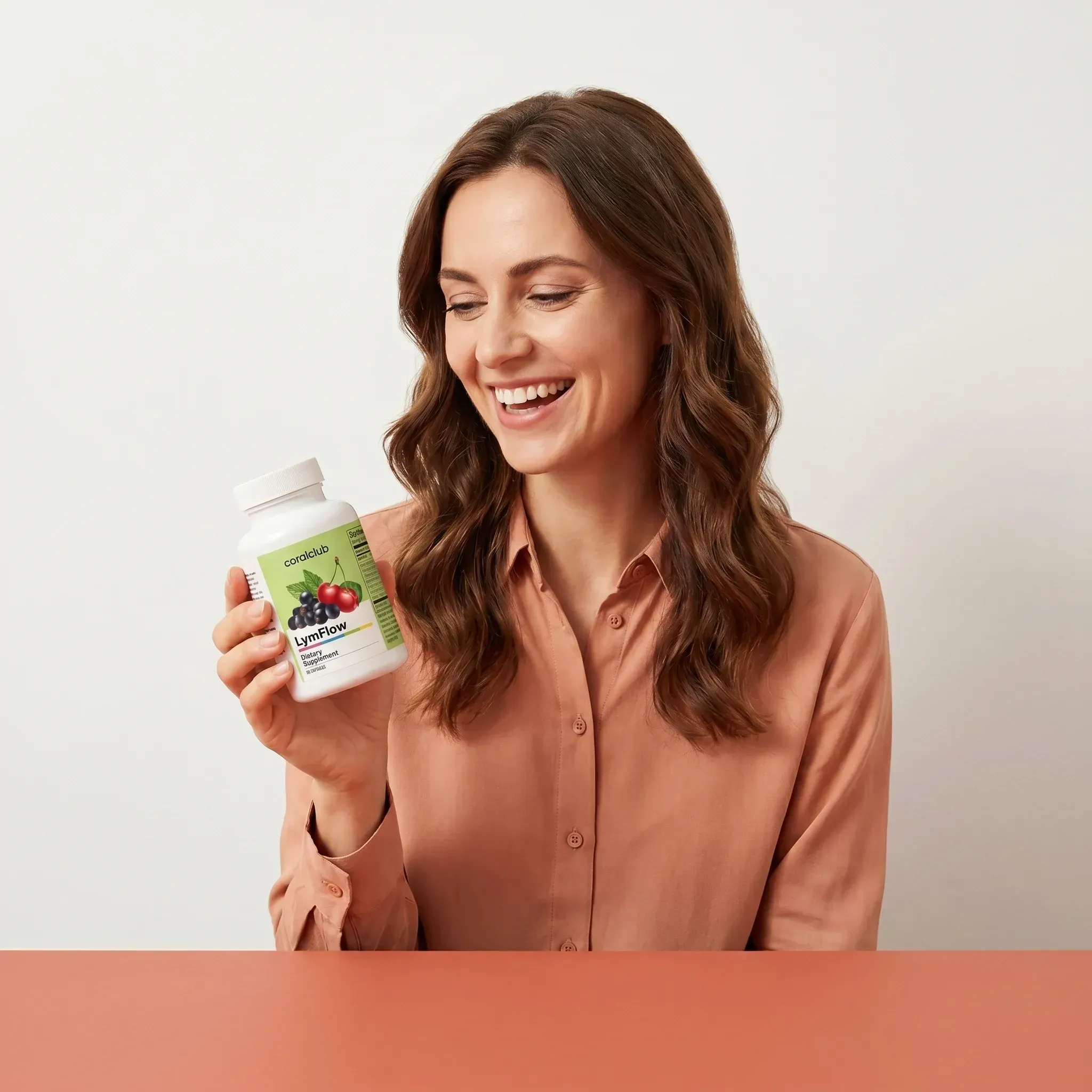 Woman smiling while holding LymFlow supplement bottle against a neutral background.