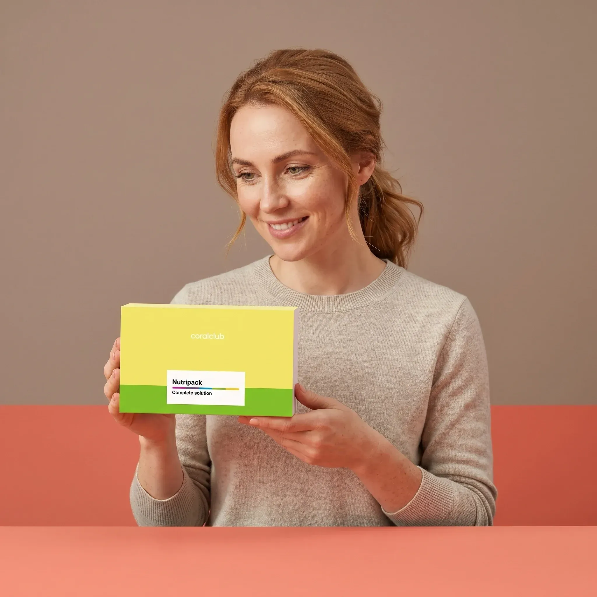 Woman holding Nutripack box, showcasing a lifestyle setting with soft pastel background.